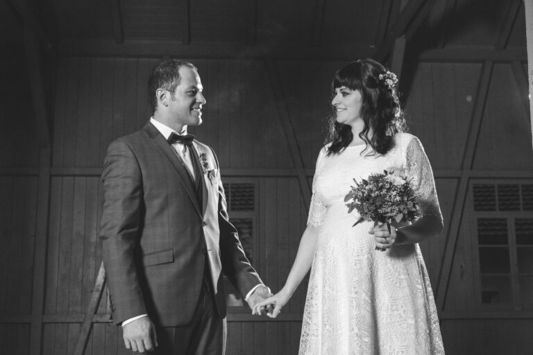Brautpaar hält sich an den Händen – Hochzeitsfoto in Schwarz-Weiß